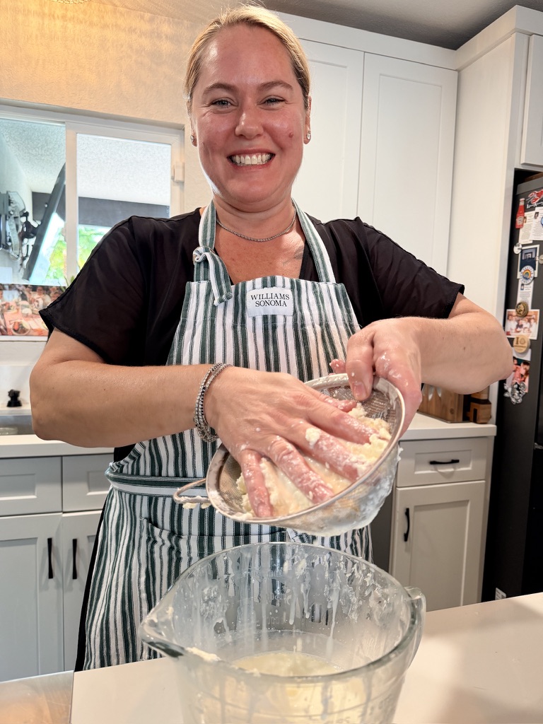 Tracy smiling as she works butter by hand in her kitchen